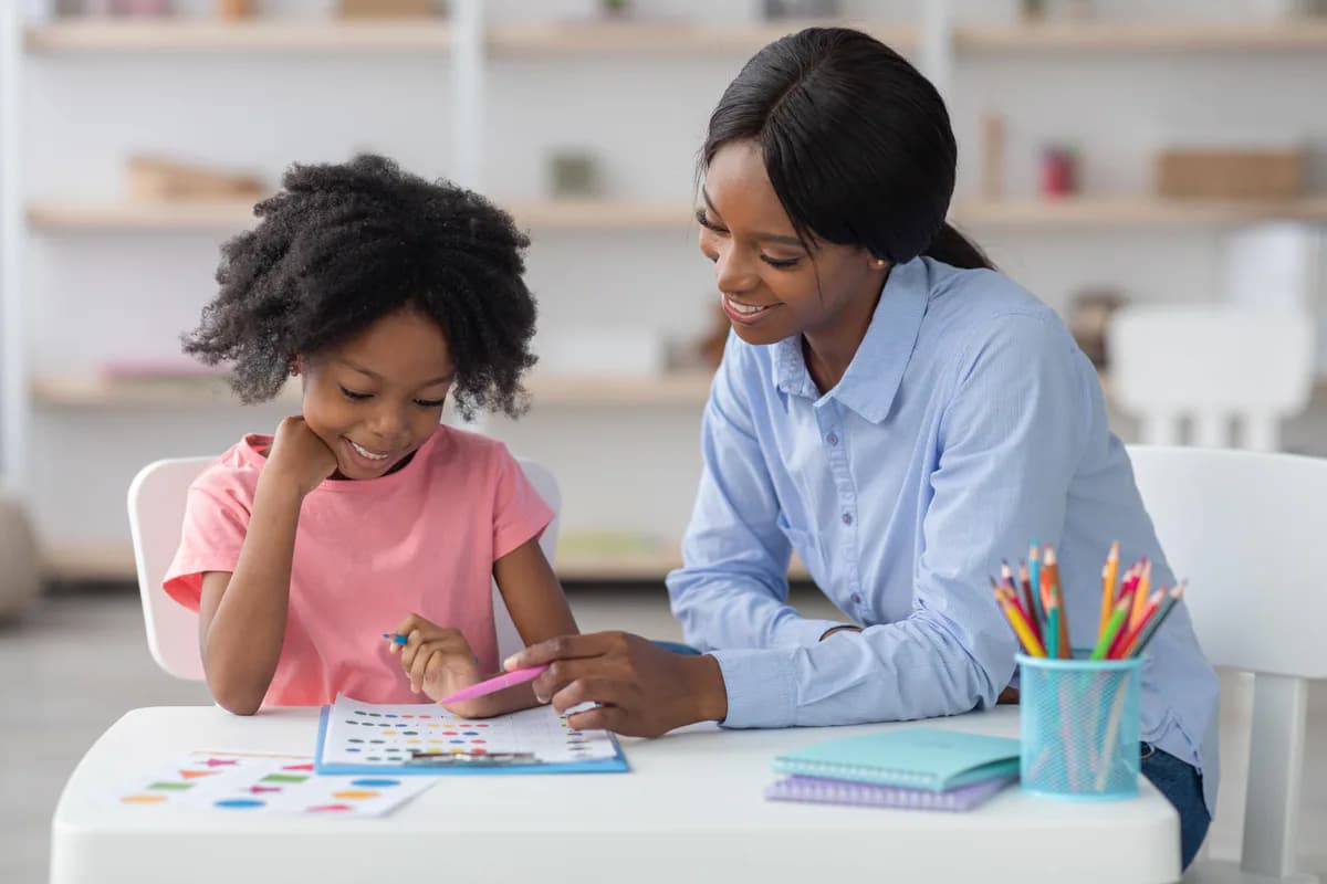 A teacher and child work together on a colorful activity sheet.