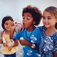 Three children blowing bubbles together.