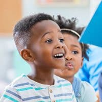 Two young students smiling with excitement in class.